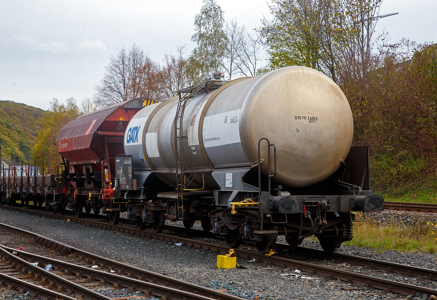 Vierachsiger-Drehgestell Kesselwagen für Salpetersäure (>97%) mit Bremserbühne, der Gattung Zacns, registriert als 33 80 7929 695-4 D-GATXD der GATX Rail Germany GmbH abgestellt, im Zugverband eines Übergabezuges der KSW, am 03.11.2022 in Herdorf auf dem Rbf. der KSW. Mieter des Wagens ist die SKW Stickstoffwerke Piesteritz GmbH (Wittenberg). 

Die Gefahrguttafel (885/2031) zeigt es auch noch an: (oben) Gefahrgutnummer 885 = stark ätzender Stoff / (unten) UN-Nummer 2031 = Salpetersäure, andere als rotrauchend, mit mehr als 70 % Säurebrandfördernd. Hier sogar (laut Anschrift) größer 97 %. Die reine Säure ist farblos und hat einen scharf stechenden Geruch. Sie wird unteranderem zur Herstellung von Sprengstoffen verwendet, was hier der Fall ist.

Der Wagen wurde 2003 vom rumänischen Wagonbauer Meva S.A. DrobetaTurnu – Severin gebaut,

TECHNISCHE DATEN:
Gattung: Zacns (Gattungszahl 7629)
Spurweite: 1.435 mm
Länge über Puffer : 12.860 mm
Drehzapfenabstand: 7.820 mm
Achsabstand im Drehgestell: 1.800 mm
Laufraddurchmesser 920 mm (neu)
Höchstgeschwindigkeit: 100 km/h
Eigengewicht: 20.250 kg
Nutzlast: 69,7 t ab Streckenklasse D3 (CM 63,7 t)
Kleinster befahrbarer Gleisbogen: R 35 m
Gesamtvolumen: 50,450 Liter
Prüfdruck: 4 bar
Zulässiger Betriebsüberdruck: 3 bar
Tankcode: L10DH
Behälterwerkstoff : Edelstahl
Intern. Verwendungsfähigkeit: RIV

Auch im dahinter befindlichen Wagen dem gedeckten Schüttgutwagen 21 80 0734 600-8 D-DB, der Gattung Tds 937, wurde ein Rohstoff für die Herstellung von Sprengstoffen transportiert und zwar Ammoniumnitrat.
