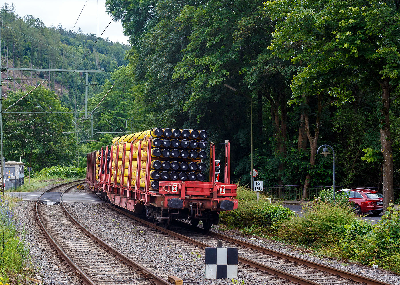 Vierachsiger Drehgestellflachwagen mit Rungen, Stirnwandklappen und Niederbindeeinrichtung, 81 80 4712 126-6 D-DB, der Gattung Sns 727, der DB Cargo AG am 20 Juni 2024 im Zugverband bei einer Zugdurchfahrt im Bahnhof Kirchen (Sieg). Hier beladen mit 36 gelb beschichteten Gasrohren bzw. HFI-längsnahtgeschweißte Stahlrohre Ø 323.9 x 12,7 (DN/NW 300 mm bzw. 12 ¾ Inch) mit gelber MAPEC® Polyethylen (HDPE)-Umhüllung), in Herstellungslänge vom 12 m. Das Metergewicht der Rohre beträgt 97,5 kg/m (ohne Umhüllung), so ist der Wagen mit ca. 45 t beladen. Der Hersteller der Stahlrohre ist die Salzgitter Mannesmann Line Pipe GmbH in Siegen (ex RW Fuchs).

In den Jahren 2001 und 2002 beschafft die DB AG vierachsige Flachwagen mit festen Rungenpaaren und niedrigen, umlegbaren Stirnborden, die mit je zwei kurzen Fallrungen gesichert werden. Die bei Grennbrier Europe Wagony Swidnica gebauten (dieser 2002) und als Sns 727 eingereihten Wagen, gleichen in vielen Komponenten den parallel beschafften Rbns 646, sind jedoch 5,91 m kürzer. Durch die reduzierte Länge und den kleineren Kurvenüberhang ließ sich die Wagenbreite um 330 mm gegenüber dem Rbns 646 vergrößern, und die Ladebreite von 2,52 m auf 2,85 m.

Wagenboden ist mit begehbaren (und nicht befahrbaren) Gitterrosten vollständig abgedeckt, die 15 hölzernen Ladeschwellen sind fest. An jeder Wagenseite befinden sich acht, innen mit Schichtholzleisten versehene Festrungenpaare (Doppelrungen), die im entlasteten Zustand oben 20 mm zur Fahrzeugmitte geneigt sind. Die in den Rungen integrierten Spannvorrichtungen verfügen über so lange Gurte, dass auch eine das G2-Profil ausnutzende Ladung gesichert werden kann. Der Sns 727 ist vorzugsweise für die Beförderung von Rohren, sowie den Transport von schweren Stahlerzeugnissen vorgesehen und überwiegend in festen Relationen im Einsatz.

TECHNISCHE DATEN:
Gattung: Sns 727
Spurweite: 1.435 mm (Normalspur)
Länge über Puffer: 20.440 mm
Drehzapfenabstand: 14.140 mm
Radsatzstand in den Drehgestellen: 1.800 mm
Ladelänge: 19.098 mm
Ladebreite: max. 2.850 mm (zwischen den Rungen)
Ladefläche: 54,4 m²
Fußbodenhöhe über SO: 1.350 mm (OK Ladeschwelle)
Rungenhöhe: 2.000 mm
Eigengewicht: ca. 26.360 kg
Zuladung bei Lastgrenze S: 63,5 t (ab Streckenklasse D); DB Netz CM 57,5 t
Max. Geschwindigkeit: 100 km/h / 120 km/h (leer)
Kleinster Gleisbogenhalbmesser: 75 m
Bauart der Bremse: KE-GP-A (LL)
Bremssohle: IB 116
Verwendungsfähigkeit: nein
