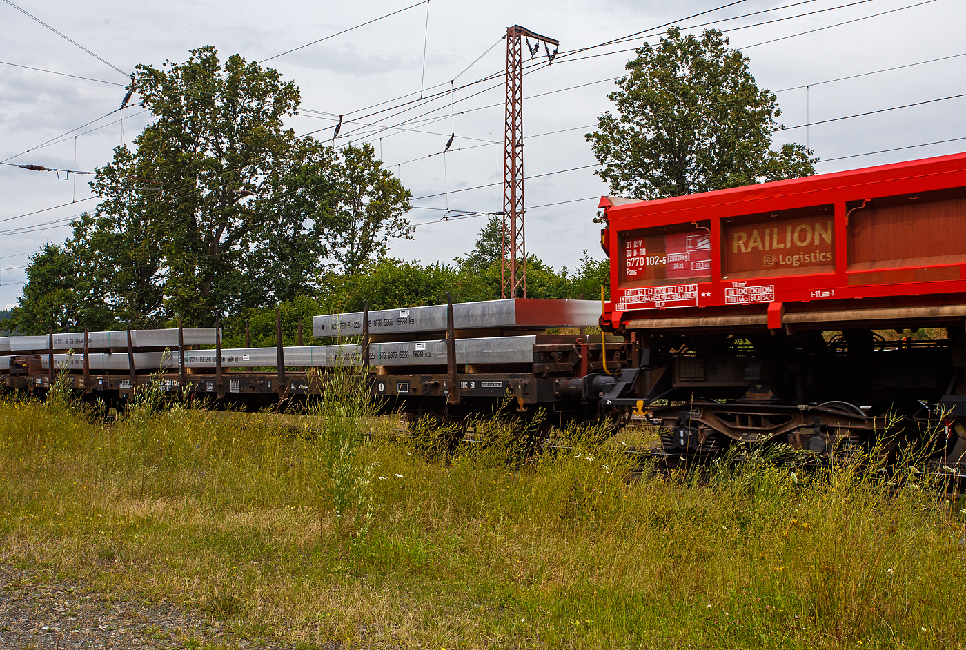 Vierachsiger Drehgestellflachwagen mit Rungen, Stirnwandklappen und klappbaren Ladeschwellen, jedoch ohne Seitenwandklappen, 31 80 3908 173-8 D-DB der Gattung Rs 684.2, der DB Cargo AG, am 19 Juli 2024 im Zugverband bei einer Zugdurchfahrt durch Rudersdorf (Kreis Siegen). Beladen ist der Wagen hier mit 9 Aluminium-Brammen mit einem Stückgewischt von 5.600 bis 6.600 kg. So ist der Wagen gemäß Lastgrenzenraster für die Streckenklasse C gut ausgeladen (aber nicht überladen). 

Der Wagen wurde 1972 von der Wagon Union (WU) in Berlin-Borsigwalde gebaut.

Mit einer Ladelänge von 18,50 m dienen diese Wagen zur Beförderung von schweren, langen Erzeugnissen der Eisen- und Stahlindustrie und Fertigbauteilen, Holz, Halbzeug, Fahrzeugen u.a.m. Für diese Transporte bieten wir Wagen in verschiedenen Ausstattungen an.

Der Wagen dient mit aufgeklappten Ladeschwellen zur Beförderung von schweren Walzprofilen und anderen sperrigen und schweren Gütern. Mit eingeklappten Ladeschwellen, also mit ebener Ladefläche, eignet er sich auch für die Beförderung schwerer Kettenfahrzeuge.

Vor den umlegbaren Stirnwandklappen sind je zwei absenkbare Rungen angeordnet. Der Wagen kann mit umgelegten Stirnwandklappen und abgesenkten Rungen gefahren werden. Die Höhe der umgelegten Stirnwandklappen über FO beträgt 38 mm. An jeder Längsseite des Wagens sind 8 Drehrungen angeordnet.

Der Fußboden besteht aus Kiefernbohlen mit den Abmessungen 70 x 180 mm. Er kann eine Radlast von 5,0 t aufnehmen. Im Fußboden sind 8 geteilte Ladeschwellen eingebaut. An einem Teil der Wagen ist in einem Drehgestell eine vom Boden aus bedienbare Feststellbremse eingebaut. Die Wagen haben eine Klotzbremse mit stufenlos, selbsttätiger Lastabbremsung. Die Bremskraft wird für jedes Drehgestell einzeln gesteuert. In jedem Drehgestell befindet sich ein Wiegeventil WM 10 und ein Doppelbremszylinder. Das Steuerventil ist im Wagenuntergestell angeordnet.

TECHNISCHE DATEN:
Erstes Baujahr der z. Z. ältesten Wagen: 1968
Spurweite: 1.435 mm (Normalspur)
Anzahl der Achsen: 4 in 2 Drehgestellen
Länge über Puffer: 19.900 mm
Drehzapfenabstand: 14.860 mm
Achsabstand in den Drehgestellen: 1.800 mm
Eigengewicht: 26.100 kg
Höhe Fußboden über SOK: 1.260 mm
Höhe der Ladeschwelle über FO: 70 mm
Max. Ladelänge: 18.500 mm
Ladefläche: 51,3 m² 
Maximale Ladegewicht: 54,5 t (ab Streckenklasse C)
Höchstgeschwindigkeit: 100 km/h (beladen) / 120 km/h (leer)
Kleinster befahrbarer Gleisbogenhalbmesser: R 35 m
Bremse: KE-GP-A (LL)
Bremssohle: IB 116
Intern. Verwendungsfähigkeit: RIV