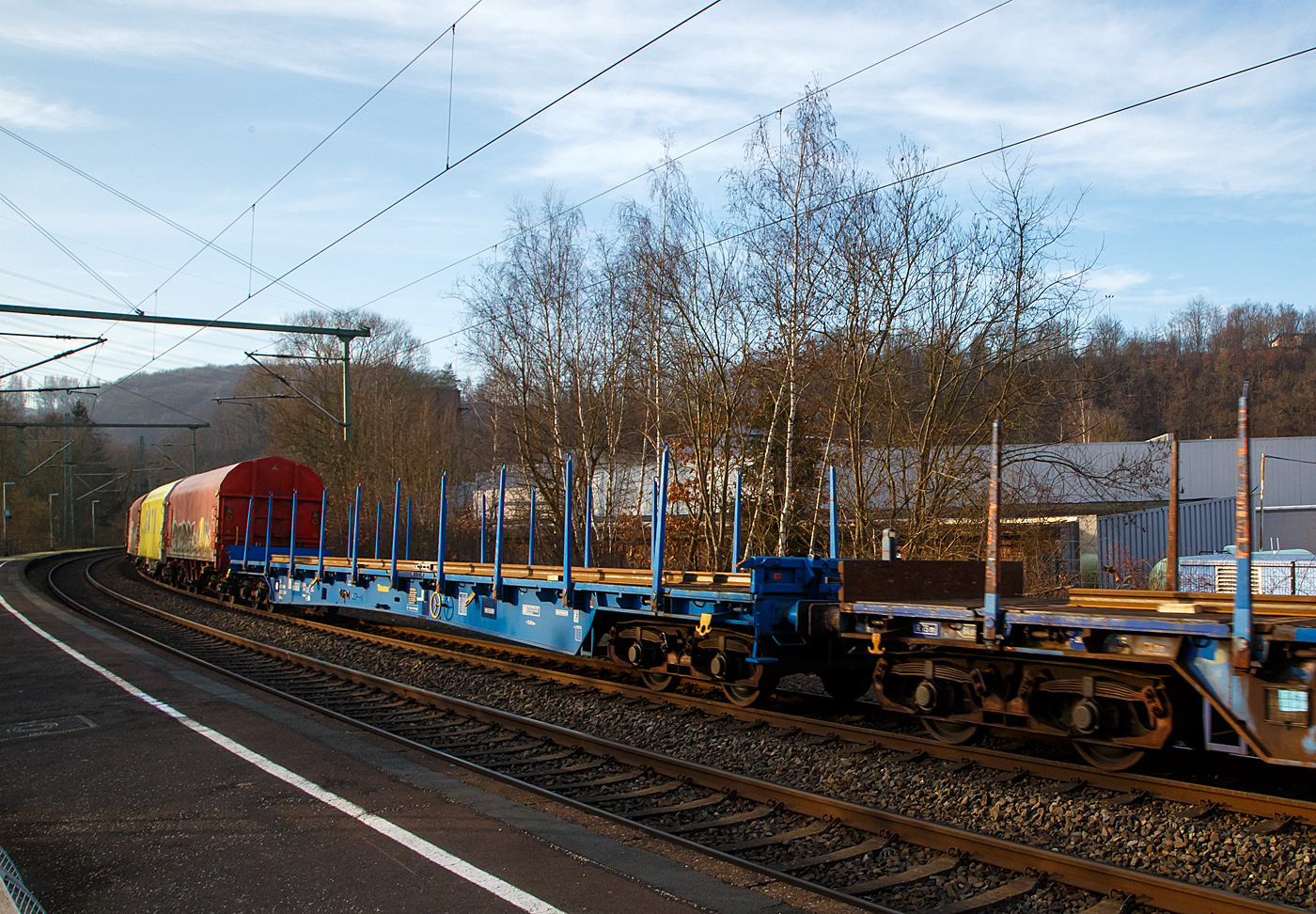 Vierachsiger langer Drehgestell-Flachwagen mit Rungen und Stirnwandklappen, 83 80 3509 014-4 D-TAUAX, der Gattung Rbkks, der irländischen Vermietungsfirma TOUAX Rail Limited, am 18.01.2023 Zugverband bei einer Zugdurchfahrt in Scheuerfeld (Sieg) in Richtung Köln.

TECHNISCHE DATEN (laut Anschriften): 
Spurweite: 1.435 mm
Länge über Puffer:  26.200 mm
Drehzapfenabstand:  21.020 mm
Achsabstand im Drehgestell: 1.800 mm
Länge der Ladefläche: 24.800 mm
Höchstgeschwindigkeit: 100 km/h (beladen) / 120 km/h (leer)
Eigengewicht:  30.200 kg
Maximale Ladegewicht:  59,8 t (ab Streckenklasse D)
Bauart der Bremse: KE-GP (LL)
Bremssohle: IB 116
Kleinster bef. Gleisbogenradius: 75 m
Intern. Verwendungsfähigkeit: Privatwagen ohne RIV

Die Bedeutung der Gattungs- und Kennbuchstaben (hier Rbkks):
R - Drehgestellflachwagen in Regelbauart
b - Ladelänge mindestens 22 m
kk - höchste Lastgrenze 40 t bis unter 60 t (über 60 t wäre es „n“)
s - Höchstgeschwindigkeit 100 km/h (beladen)