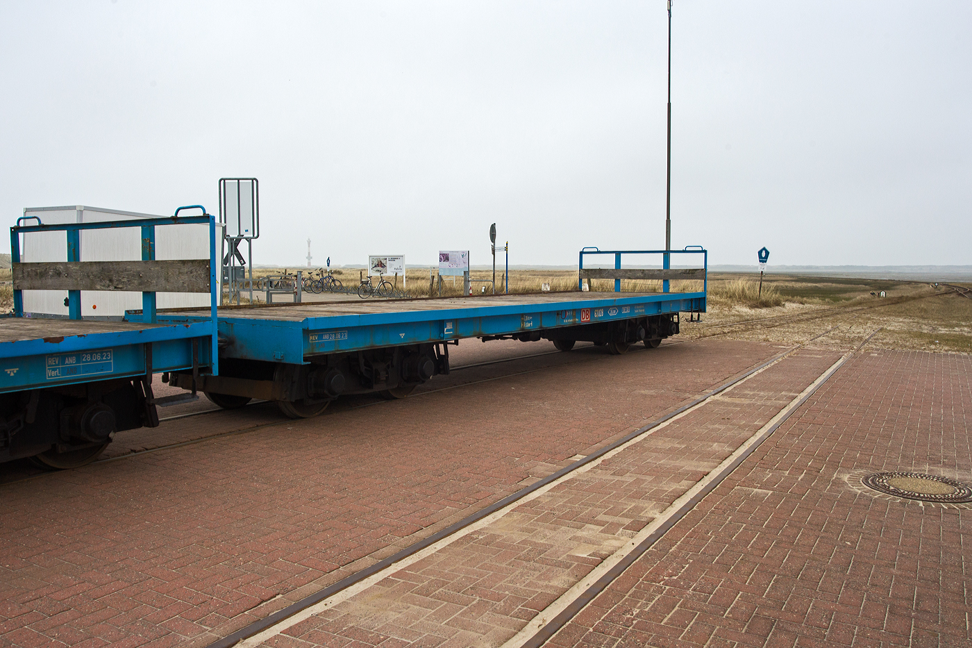 Vierachsiger schmalspuriger Flachwagen DB 63 028 der DB Fernverkehr AG Standort Wangerooge (Wangerooger Inselbahn / SIW - Schifffahrt und Inselbahn Wangerooge) am 13 März 2024 eingereiht in einen kurzen Güterzug beim Westanleger der ostfriesischen Insel Wangerooge.

Der Wagen wurde 1997 vom DB-FIW Görlitz gebaut.

TECHNISCHE DATEN:
Spurweite: 	1.000 mm (Meterspur)
Länge über Puffer: 11.000 mm
Drehzapfenabstand: 7.200 mm
Ladefläche: 26,0 m²
Höhe der Ladefläche: 1.000 mm
Eigengewicht: 12.000 kg
Max. Zuladung: 32.000 kg
Bremse: KE-P
Kupplungstyp: Balancierhebel- bzw. Ausgleichkupplung (zp2)
