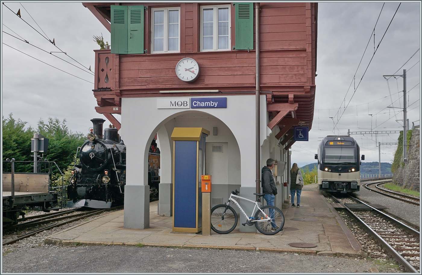 Während in Chamby der CEV MVR ABeh 2/6 7504  Vevey  als R34 nach Montreux einfährt, versteckt sich hinter dem schön hergerichteten Empfangsgebäude auf Gleis 3 die HG 2/4 N° 3 der Blonay Chamby Bahn.

4. Oktober 2025