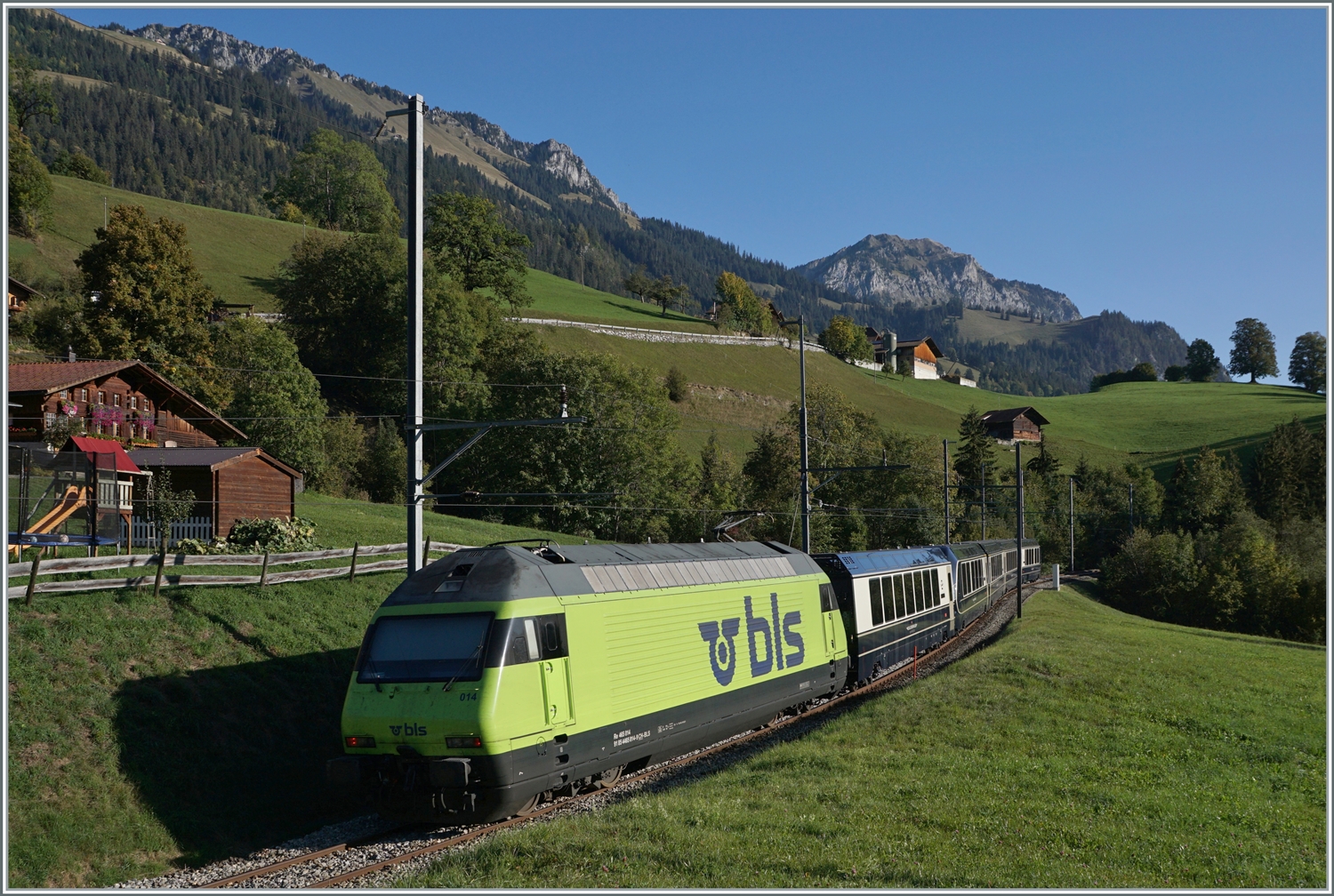 Weitaus besser zu sehen: die BLS Re 465 014 (UIC 91 85 4465 014-9) ist kurz nach der Haltestelle Enge im Simmental, welche der Zug ohne Halt passiert hat, mit dem GoldenPass Express GPX 4064 von Montreux nach Interlaken Ost unterwegs.

7. Okt. 2023