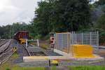 
Eine nagelneue Windhoff Rangieranlage an der Tonverladerampe in Weilburg-Löhnberg, hier am 20.09.2014 (Aufnahme vom Bü).
 
Auch heute wird noch an zahlreichen Ladestellen Ton auf die Bahn umgeschlagen. Hier an der Hochrampe in Löhnberg wird Material aus den LKWs in die Tonwagen, der Gattung Tamns 895, abgekippt. Das Rangieren der Wagen (den Wagenzug weiter bewegen damit ein leerer Wagen an der Rampe steht) übernimmt diese ferngesteuerte Rangieranlage.  Es ist eine 2014 von der Windhoff Bahn- und Anlagentechnik GmbH in Rheine gebaute Rangieranlagen mit umsteuerbarem Seilzug. Ein geschlossenes Seilzugsystem liegt ständig längs im Rangiergleis, die Ankopplung an den Zug erfolgt über einen Pufferwagen, welcher über den stirnseitigen Zughaken wie eine Lokomotive an den Zug gekuppelt wird. Vom Grundsatz her ist es eine Standseilbahn, bestehend aus Antriebstation, Umlenkstation und dem am Zugseil befestigten Pufferwagen.

Technische Daten:
Hersteller: Windhoff Bahn- und Anlagentechnik GmbH, Rheine
Baujahr: 2014
Eigengewicht: 11.000 kg
max. Förderkraft: 50 kN
Geschwindigkeit (Lastfahrt): 0,0 bis 0,3 m/s (entspr. max. 1 km/h)
Geschwindigkeit (Leerfahrt): 0,0 bis 0,6 m/s