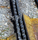 Deteilbild der zwei lamelligen (doppelte) hochliegenden Zahnstangen vom System Abt, hier der tpc BVG - Chemin de fer Bex–Villars–Bretaye, hier am 10 September 2023 beim Haltepunkt Bouquetins auf 1.758 m ü. M, der Strecke 128 (Villars-sur-Ollon–Col-de-Bretaye).

Die tpc Strecke BVB, deutsch Bex–Villars–Bretaye-Bahn, ist eine 17 km lange Schmalspurbahn in der Spurweite 1.000 mm mit gemischtem Adhäsions- und Zahnradbetrieb. Das 4,65 km Teilstück (BAV-Strecke 128) von Villars-sur-Ollon (1.252 m ü. M.) auf den Col-de-Bretaye (1.808 m ü. M) ist vollständig mit einer Zahnstange System Abt versehen und hat eine maximale Steigung von 170 Promille.

Das Zahnstange System Abt:
Das System Abt mit Lamellenzahnstangen ist bezeichnet nach ihrem Erfinder Carl Roman Abt. Es kann als Weiterentwicklung zum System Riggenbach gesehen werden. Zwei oder drei Lamellen liegen gegeneinander versetzt mit den Zähnen nach oben im Gleis, ja nach Triebfahrzeug greift ein entsprechendes Zahnrad bzw. mehre Zahnräder von oben ein. Bei Bahnen mit reinem Zahnradbetrieb ist in flachen Bereichen auch nur eine Lamelle (Zahnstange) verbaut, da die Loks/ Triebfahrzeuge meist keinen Adhäsionsantrieb besitzen. 

Besonderer Vorteil bei Verwendung mehrerer Lamellen ist die gleichmäßigere Kraftübertragung, da sich immer mindestens ein Zahn im Eingriff befindet; dabei ist allerdings eine Torsionsfederung der Triebzahnräder erforderlich. Die relativ schmalen Stangen sind zur Anpassung an beliebige Bogenradien genügend biegbar. Durch die Vervielfältigung der Stangen blieb die Kontaktfläche zwischen Zahnrad und Zahnstangen ausreichend groß. Die Breite der Lamellen hängt vom größten auftretenden Zahndruck ab und variiert zwischen 16 und 40 mm (bei der MRS Logística S.A. eine Erzbahn in Brasilien auch 60 mm), ihr Abstand beträgt mehrheitlich 32–40 mm. Die Zahnteilung beträgt üblicherweise 120 mm, anstelle der bei anderen Systemen sonst oft üblichen 100 mm. Wie bei den anderen Systemen auch kamen hier ebenfalls viele unterschiedliche Höhenlagen zur Ausführung, wie z.B. hier hochliegende (über der Gleisoberkante).

Diese Mehrlamellenbauart erreichte weltweit die größte Verbreitung. Ein besonderer Vorteil bei Verwendung mehrerer Lamellen ist die ruhige, stoßfreie und betriebssichere Kraftübertragung durch die um einen halben bzw. drittel Zahn versetzte Teilung der Lamellen; dabei ist allerdings eine Torsionsfederung der Triebzahnräder-Scheiben gegeneinander erforderlich, um eine annähernd gleichmäßige Aufteilung des Zahndrucks auf die Lamellen zu erreichen. Die Zahnstangeneinfahrten mit gefederter Spitze und kleineren Zähnen waren von Anfang an Teil des Systems.

Das System wurde insbesondere für den durchgehenden Betrieb auf Strecken mit Zahnstangen- und Adhäsionsabschnitten entwickelt, die Zahnräder liegen generell oberhalb der Schienenoberkante. 